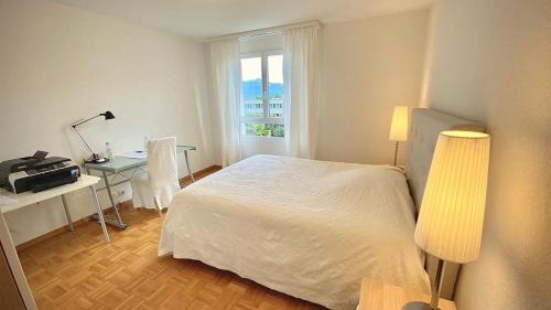 a bedroom with a bed and a desk and a window at Close to the lake and very spacious 3 bedroom in Lausanne