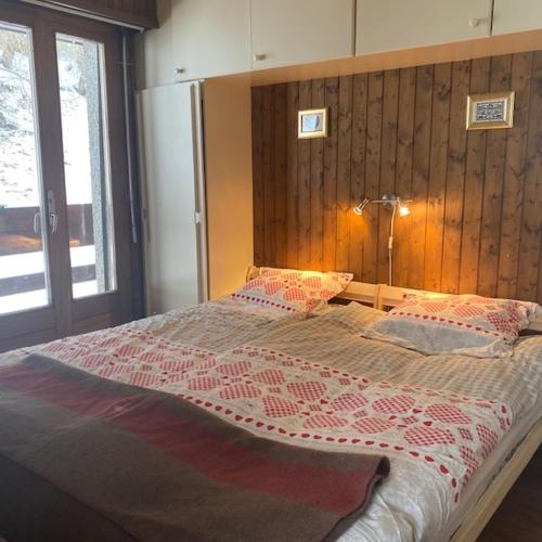 a bedroom with a large bed with a wooden wall at Immeuble Mont Noble in Les Collons