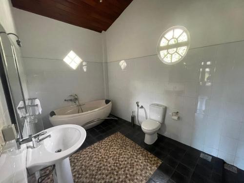 a bathroom with a sink and a toilet and a tub at Una Beach Hotel & OLU Cafe in Unawatuna