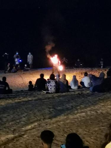 a group of people sitting on the beach at night at The Sky Inn in Kuantan
