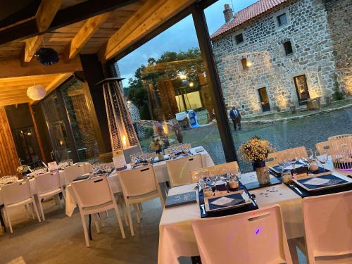 a dining room with tables and chairs in front of a building at Domaine de la Planche de Melussac in Cussac-sur-Loire