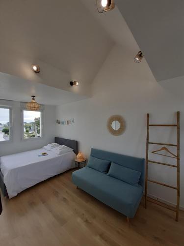 une chambre avec un lit et un canapé bleu dans l'établissement Studio calme 20m² à 500 mètres de la plage/ centre, à Saint-Pierre-Quiberon