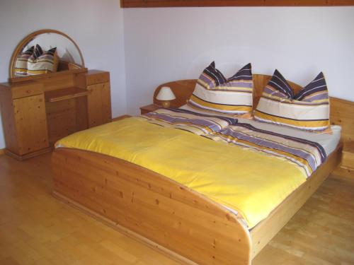 una camera da letto con letto in legno, cuscini e specchio di Villa Burgblick ad Annenheim
