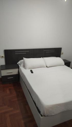 1 cama con sábanas blancas y almohadas en una habitación en Vigo Céntrico y próximo a las playas en Vigo
