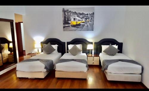 a hotel room with two beds and a yellow train at Hotel Excelsior in Lisbon