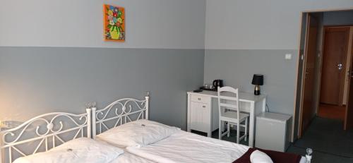 a bedroom with a white bed and a desk at Hotel Kreator-Sport in Kraków