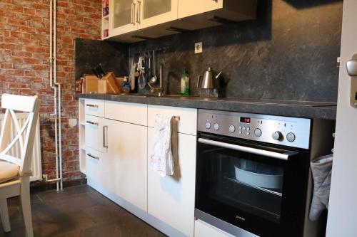 a kitchen with white cabinets and a black oven at Im Schnuckenbau, Ferienhaus in Schneverdingen