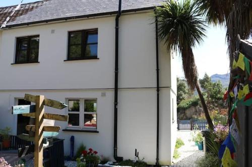 a white house with a palm tree in front of it at Tulloch (2 Hamilton Place) in Kyle of Lochalsh