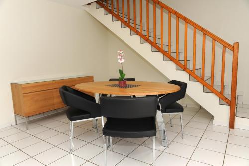 a dining room table with black chairs and a staircase at A la Suite du Jardin de l'Isle in Vienne