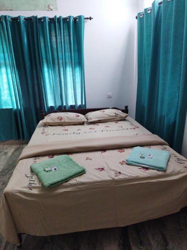 a bedroom with two beds with blue curtains at Jayuz Homestay & Foodies in Kozhikode
