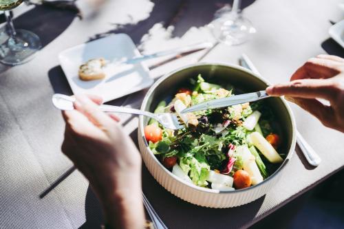 a bowl of salad on a table with people eating it at Pflugwirts Hotel und Gasthaus in Oberkirch