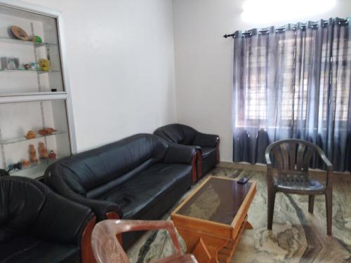 a living room with a black couch and a chair at Jayuz Homestay & Foodies in Kozhikode