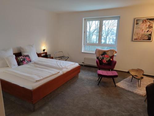 - une chambre avec un grand lit et une chaise dans l'établissement Eppelborner Hof, à Eppelborn
