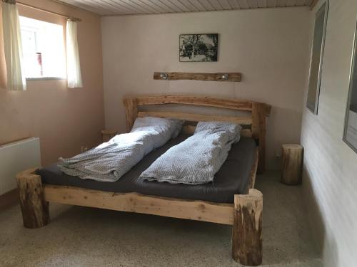 a bedroom with a wooden bed with two pillows at Okker Gokker Gården in Allingåbro
