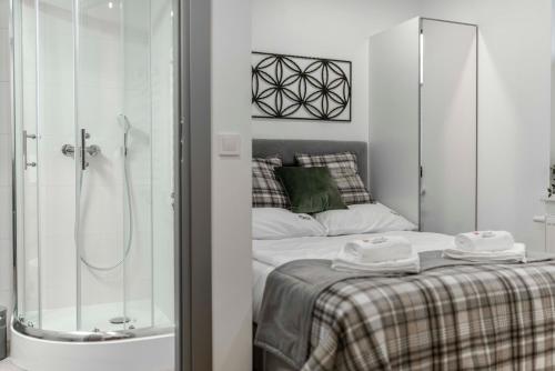 a small bedroom with a shower and a bed at Apartamenty Kwiatowa w Szczawnicy BEZPŁATNY PARKING in Szczawnica