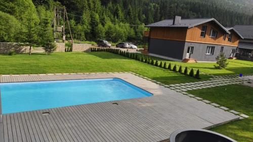 a backyard with a swimming pool and a house at Chalet Venterivka in Tatariv