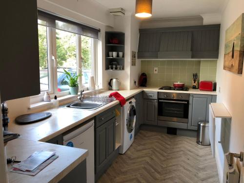een keuken met een wastafel en een wasmachine bij The Grey Cottage in Blackford