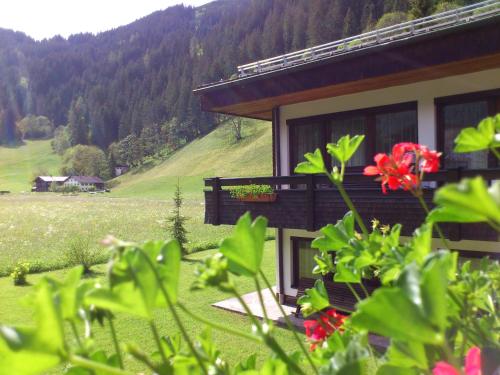 a house with a balcony with flowers in front of it at Ferienwohnungen Bailom in Elbigenalp