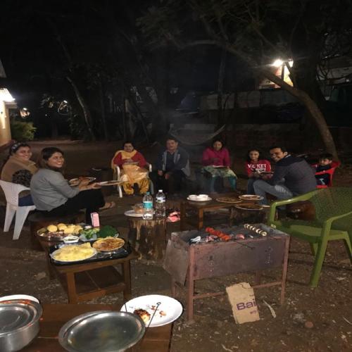 a group of people sitting around a table at night at Citadel Resort in Panchgani