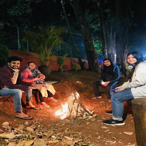 a group of people sitting around a fire at Citadel Resort in Panchgani