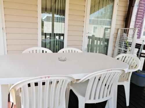 Una mesa blanca en un porche con sillas blancas. en Bungalow cosy à Onzain avec terrasse & piscine partagée, en Onzain