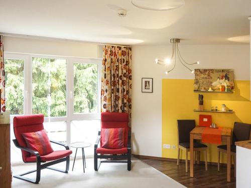 salon z czerwonymi krzesłami i stołem w obiekcie Apartment Heller am Hasselkopf w mieście Braunlage