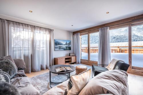 un soggiorno con un divano e una grande finestra di Apartment Ophite Méribel - by EMERALD STAY a Les Allues