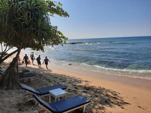 a group of people walking on the beach at Eagle Homestay in Tangalle
