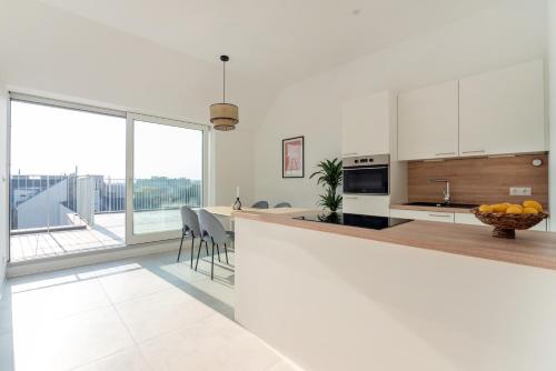 a kitchen with white cabinets and a large window at Sophienne Apartments in Vienna