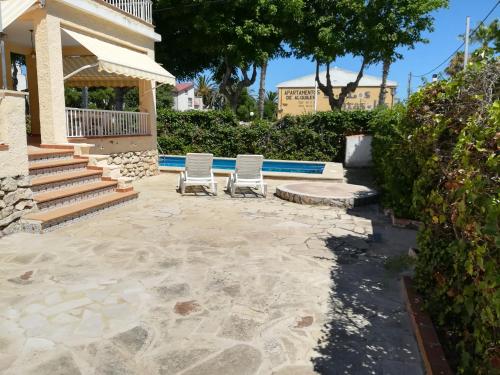 a patio with two white chairs and stairs at Chalet a 90 m playa,wifi y piscina privada in Benicarló