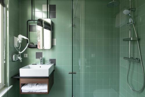 a green bathroom with a sink and a shower at Alex Maastricht in Maastricht