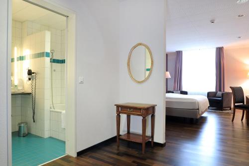 a bedroom with a bed and a bathroom with a mirror at Hotel Banana City Winterthur in Winterthur