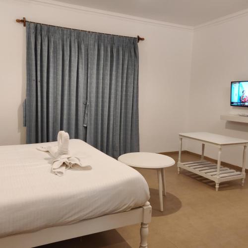 a bedroom with a bed and a table and a television at Studio Apartment by Leela Homes in Arpora