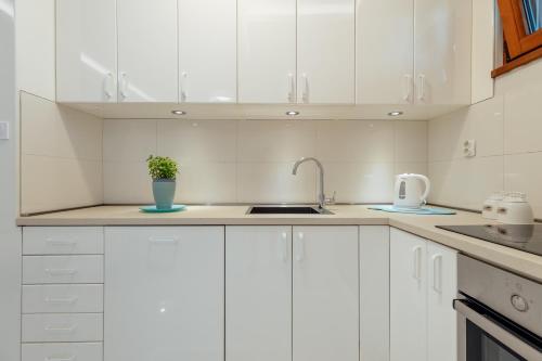 a white kitchen with white cabinets and a sink at Apartments Dabinovic in Kotor