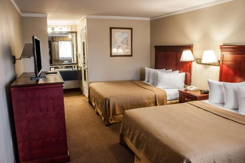 a hotel room with two beds and a flat screen tv at Quality Inn & Suites Fife Seattle in Fife