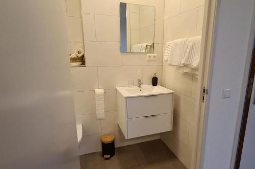 a white bathroom with a sink and a mirror at B&B Het Groene Hart in Nieuwkoop