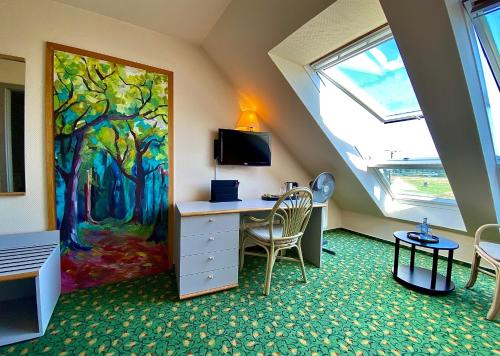 a room with a desk and a painting on the wall at Hotel am Müritz-Nationalpark in Waren