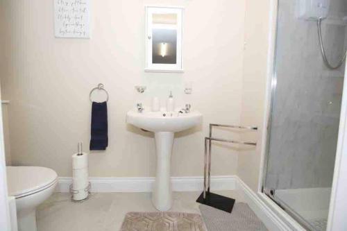 y baño blanco con lavabo y ducha. en “John Bs” 1 Bedroom Apartment in Ardara, en Ardara