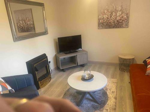 sala de estar con sofá, mesa y TV en “John Bs” 1 Bedroom Apartment in Ardara, en Ardara