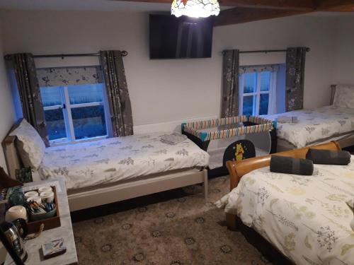 a bedroom with two beds and two windows at Upper Eyton Farmhouse B&B in Shrewsbury