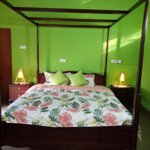 a bedroom with a bed with green walls and two lamps at Palms Villa in Negombo