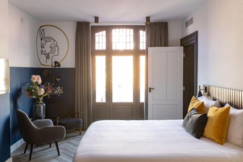 een slaapkamer met een bed, een stoel en een raam bij Alex Maastricht in Maastricht