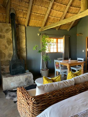 ein Wohnzimmer mit einem Kamin, einem Tisch und Stühlen in der Unterkunft Berghouse and Cottages in Langkloof