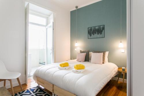 Un dormitorio con una gran cama blanca con sombreros amarillos. en The Graceful Escape, en Lisboa