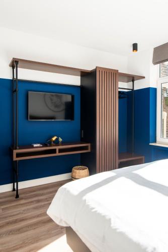 a bedroom with a blue accent wall and a tv at Alex Maastricht in Maastricht