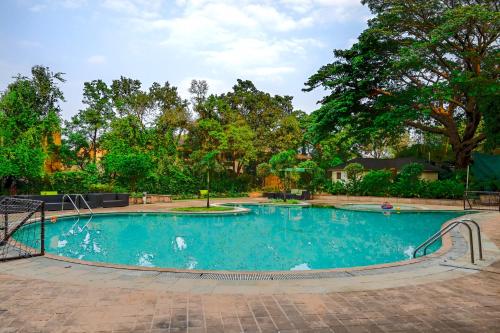 a large swimming pool in a yard with trees at Citrus Hotel Lonavala in Lonavala
