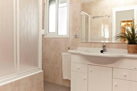 Baño blanco con lavabo y espejo en Homing Cambrils 23, en Cambrils