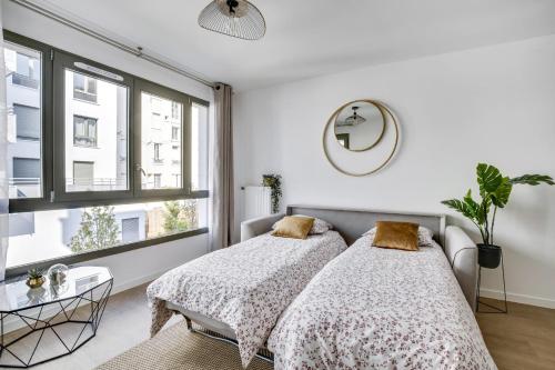 two beds in a bedroom with a window at Superbe appartement avec balcon et parking proche Paris in Saint-Denis