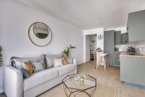 un salon avec un canapé et une table en verre dans l'établissement Superbe appartement avec balcon et parking proche Paris, à Saint-Denis