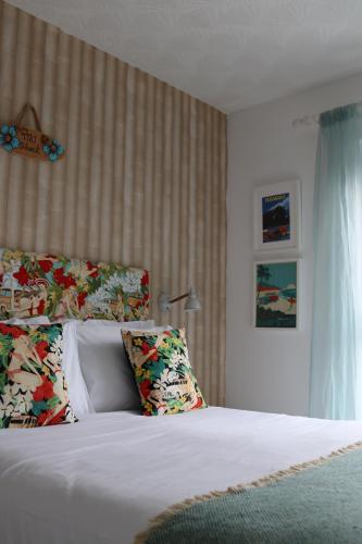 a bedroom with a bed with white sheets and pillows at Porth Beach Hotel in Newquay